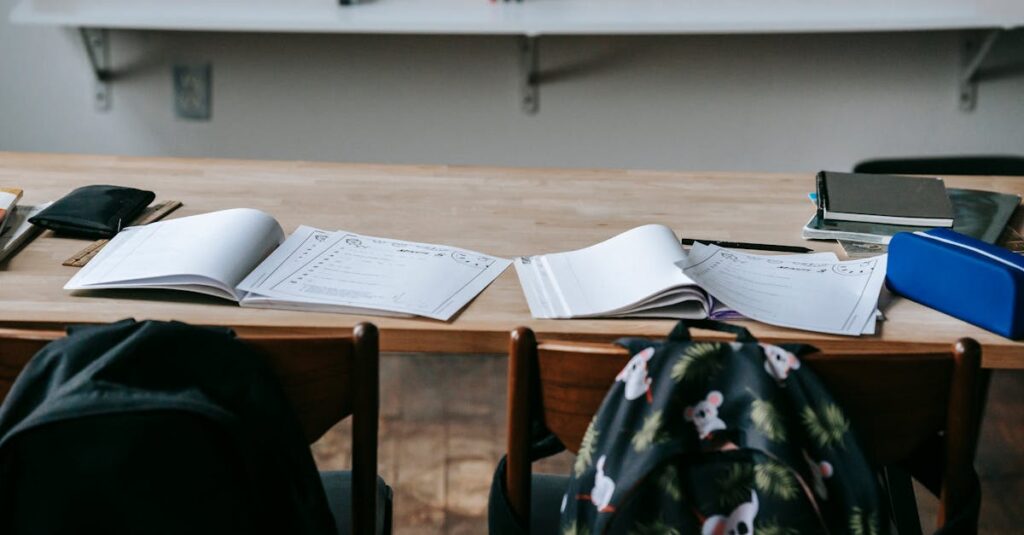 School desk with opened textbooks and stationery against whiteboard in modern light classroom